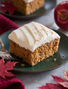 Close up image of single slice of applesauce cake on a green plate with a second slice in the background.