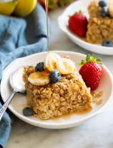 Slice of baked oatmeal topped with fresh fruit and maple syrup.