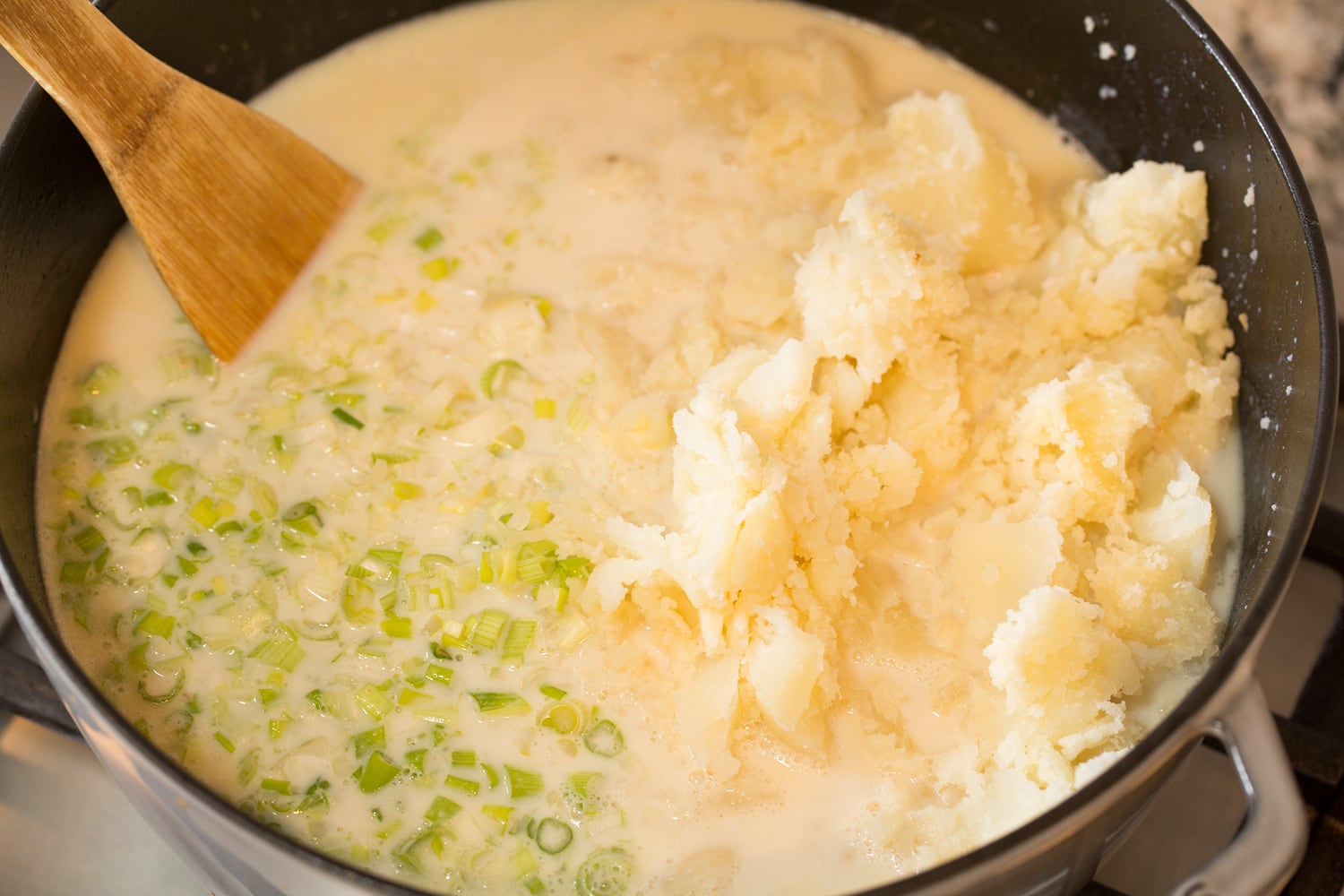 Adding milk and baked potatoes to soup.