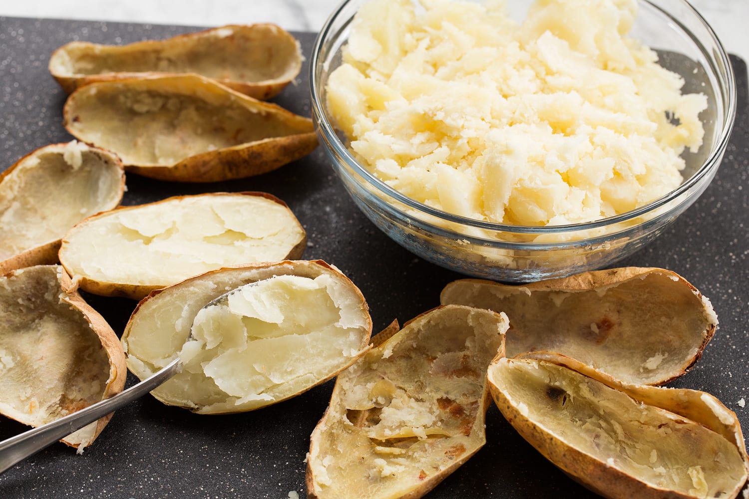 Scooping out potato flesh from skins.