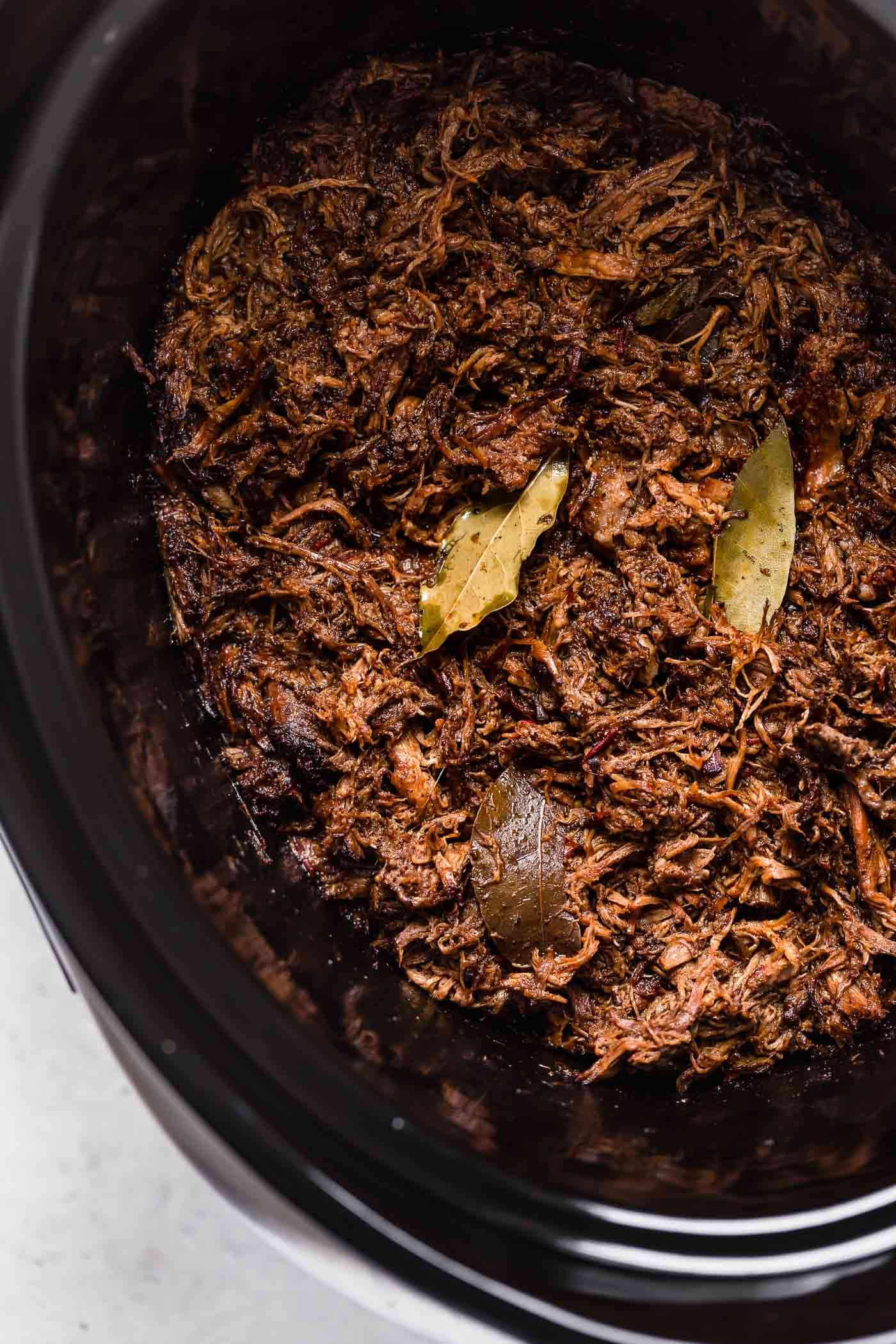 Shredded barbacoa beef in a crock pot.