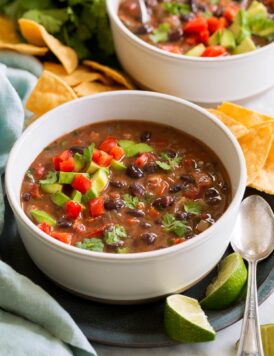 Serving of homemade black bean soup topped with tomatoes, avocado and cilantro.