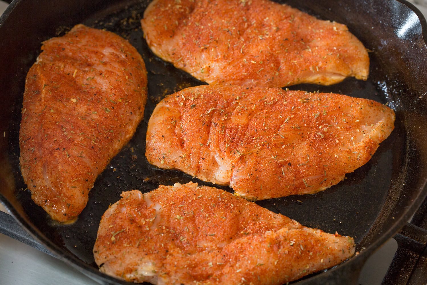 Chicken shown in skillet before cooking second side.