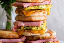 Stack of breakfast sandwiches with eggs, meat and cheese.