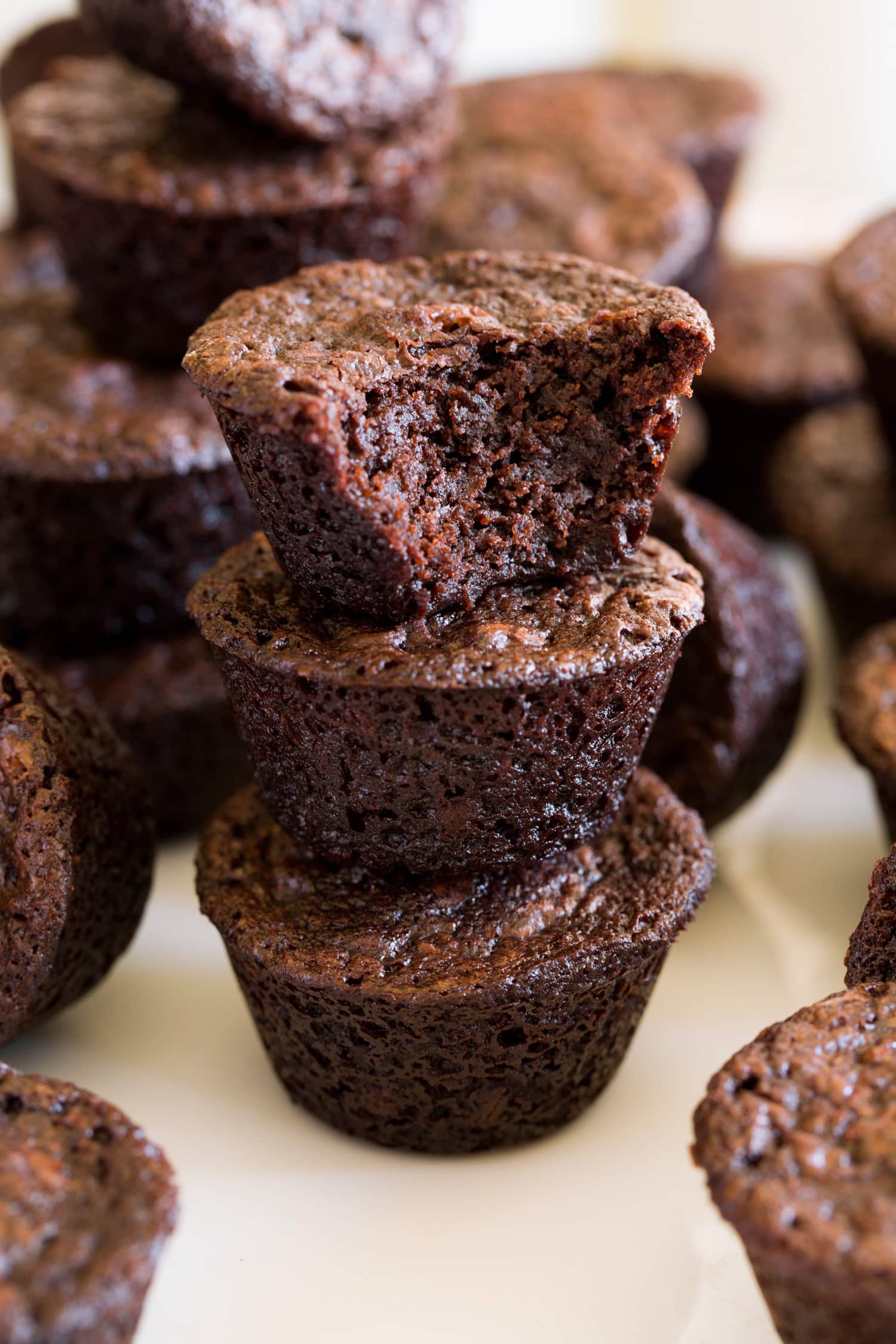 Close up photo of brownie bites stacked with one bitten into showing texture.