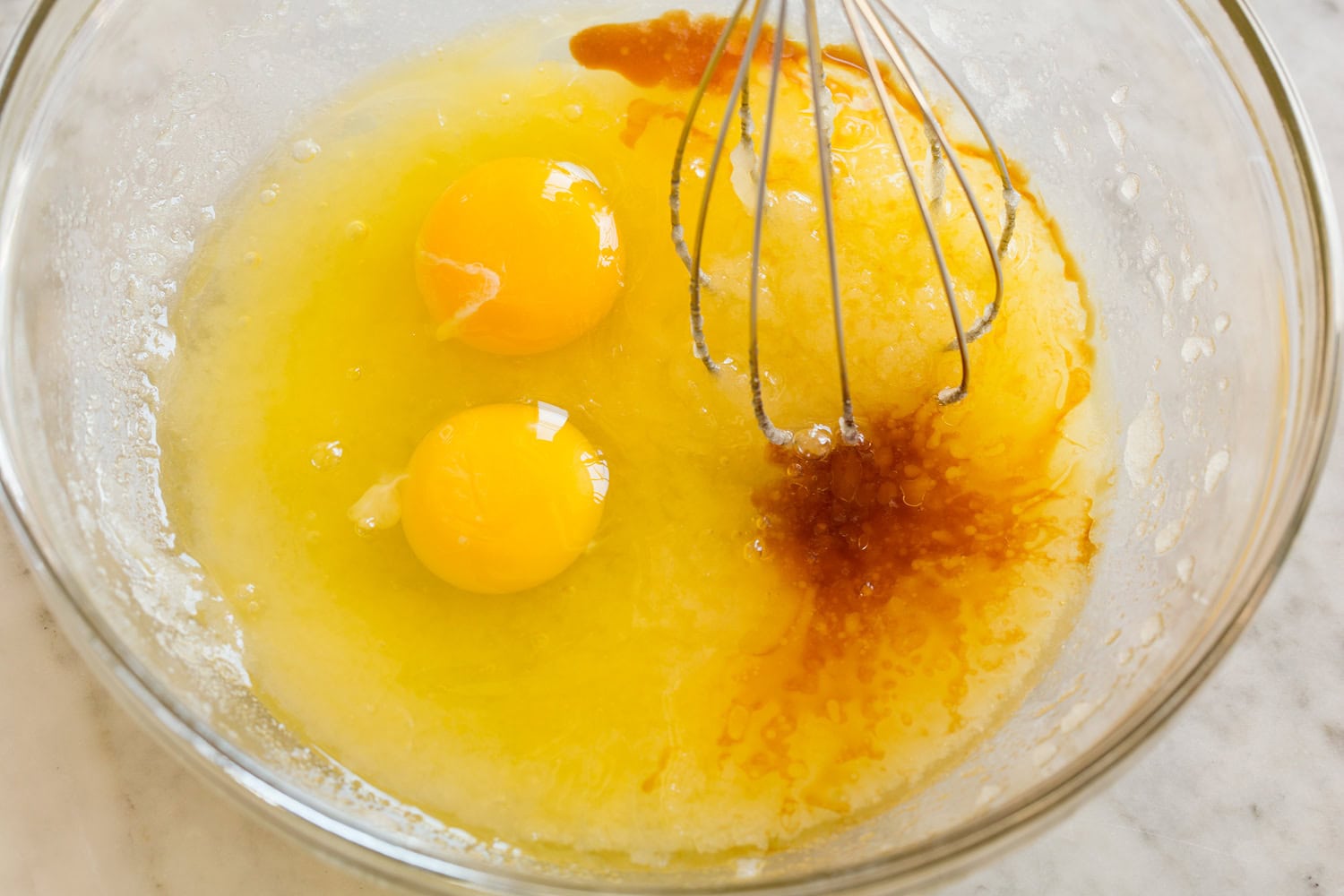 Eggs and vanilla with melted butter mixture in mixing bowl.