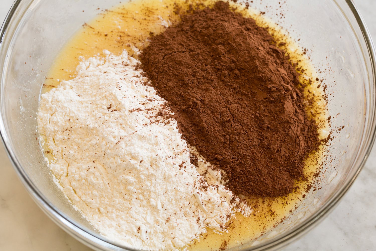 Cocoa and flour added to butter mixture in mixing bowl.