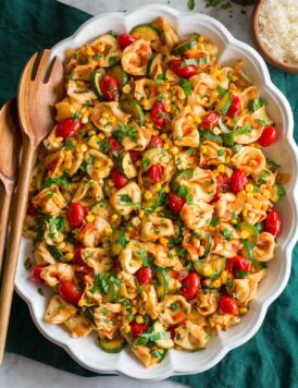 Photo: Tortellini shown in an oval platter from overhead. Platter is on a green cloth on a marble surface.