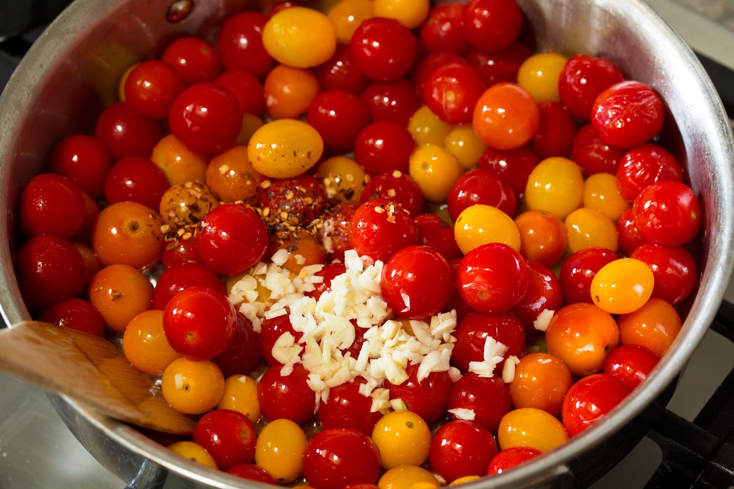 Garlic and red pepper flakes being added to tomato sauce.