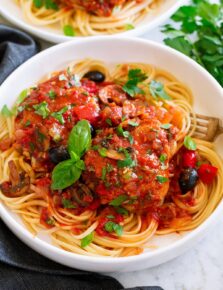 Chicken cacciatore shown served over pasta in a white bowl.