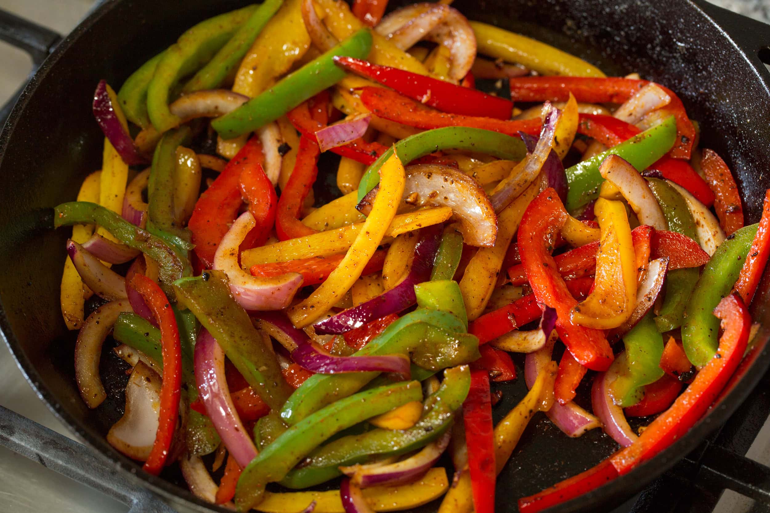 Cooked bell peppers and onions in skillet.