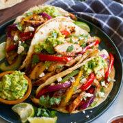 Three chicken fajitas in flour tortillas shown with various toppings.