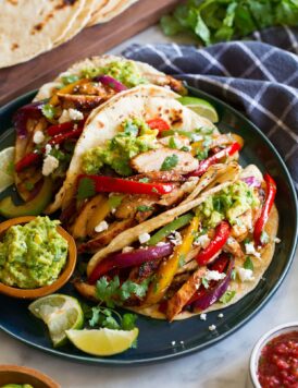 Three chicken fajitas in flour tortillas shown with various toppings.