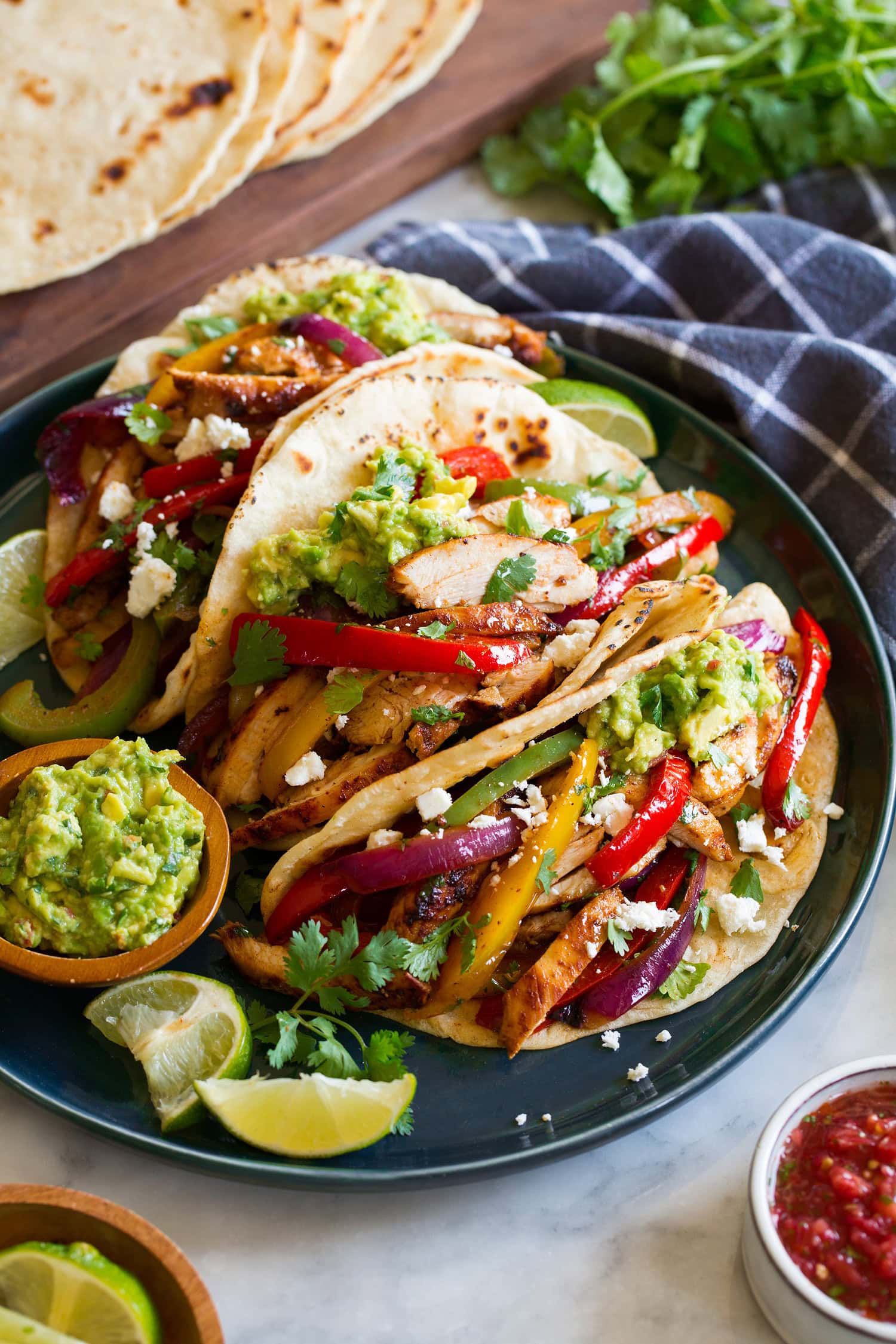 Three chicken fajitas in flour tortillas shown with various toppings.