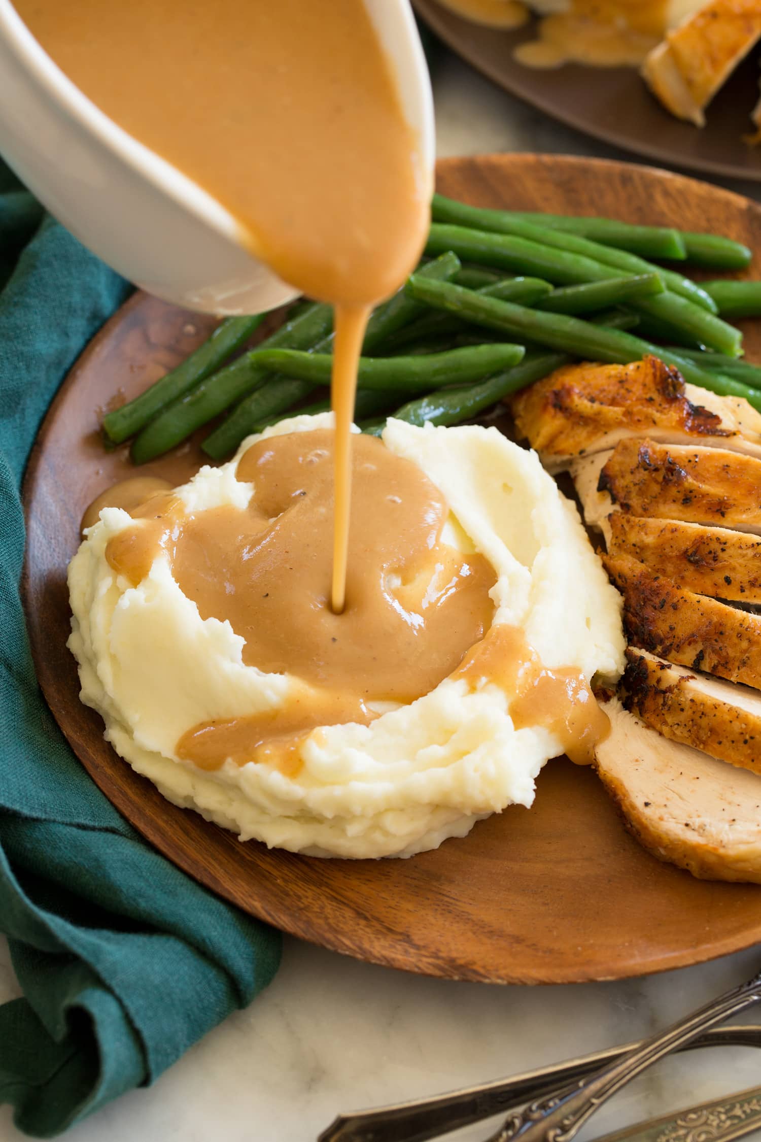 Gravy being poured over mashed potatoes.