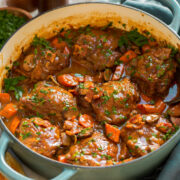 Coq au vin shown in a braiser pot.