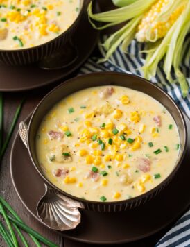 Corn Chowder in two serving bowls. Chowder has fresh pieces of corn, chunks of ham and is garnished with chives.