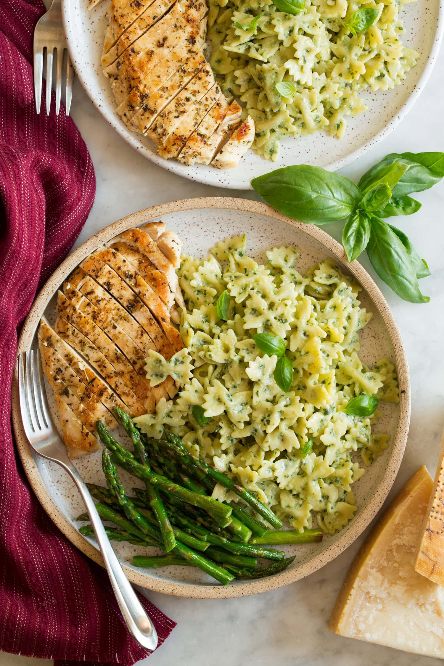 Creamy pesto pasta served with seared chicken breasts and asparagus as a serving suggestion.