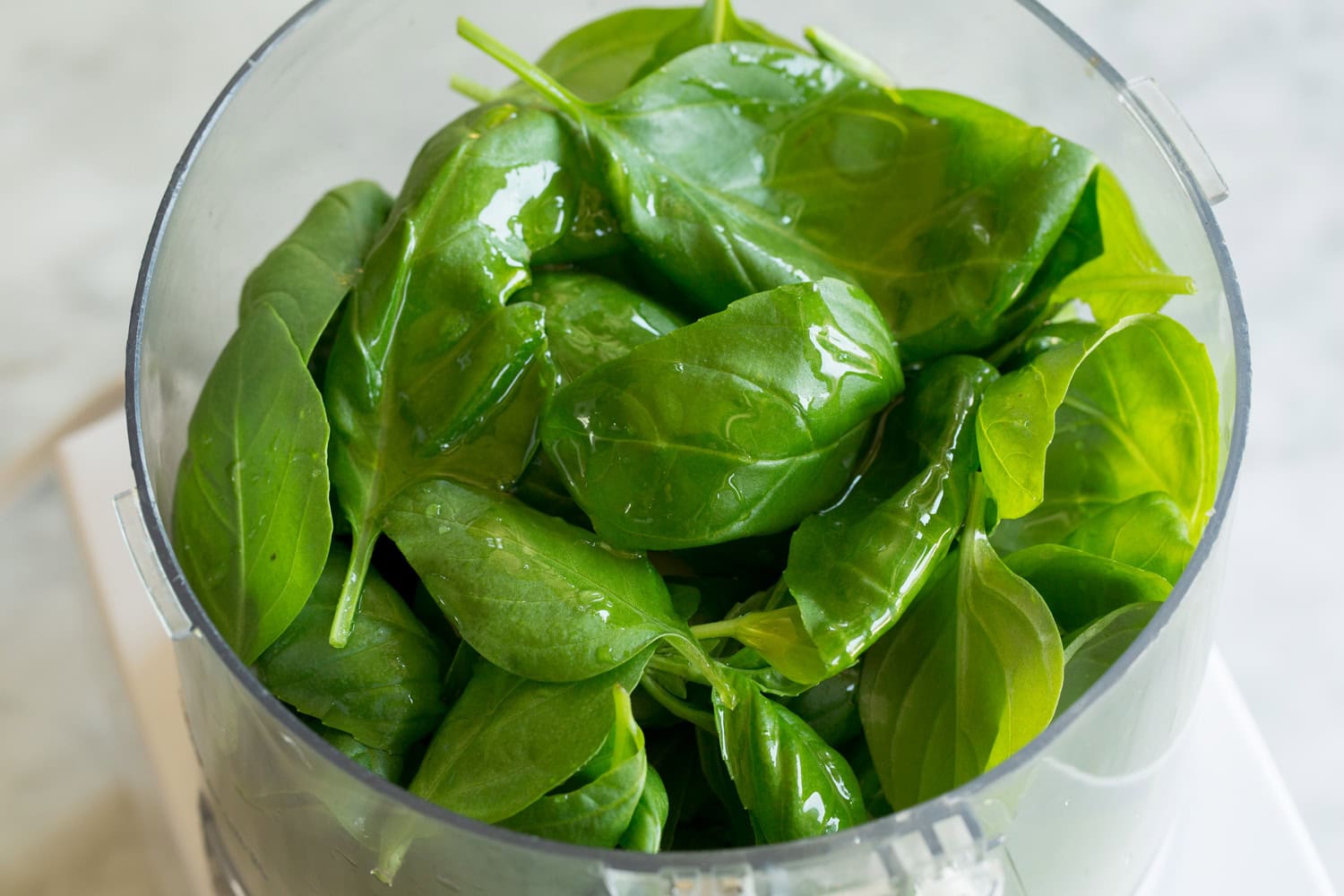 Fresh basil, oil and water in a food processor.