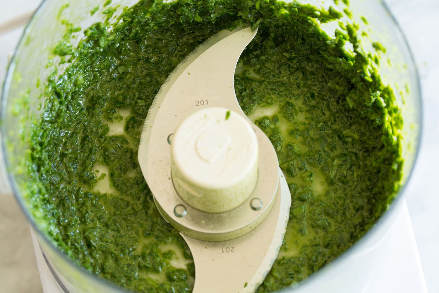 Minced basil oil mixture in food processor.