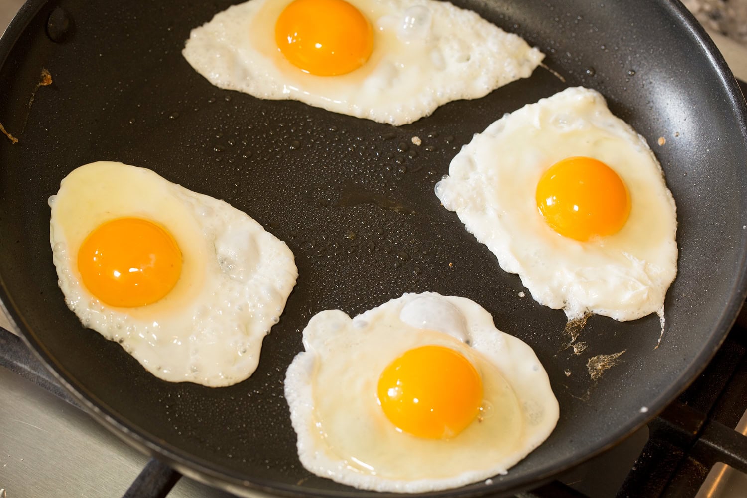 Four fried eggs in a dark skillet.