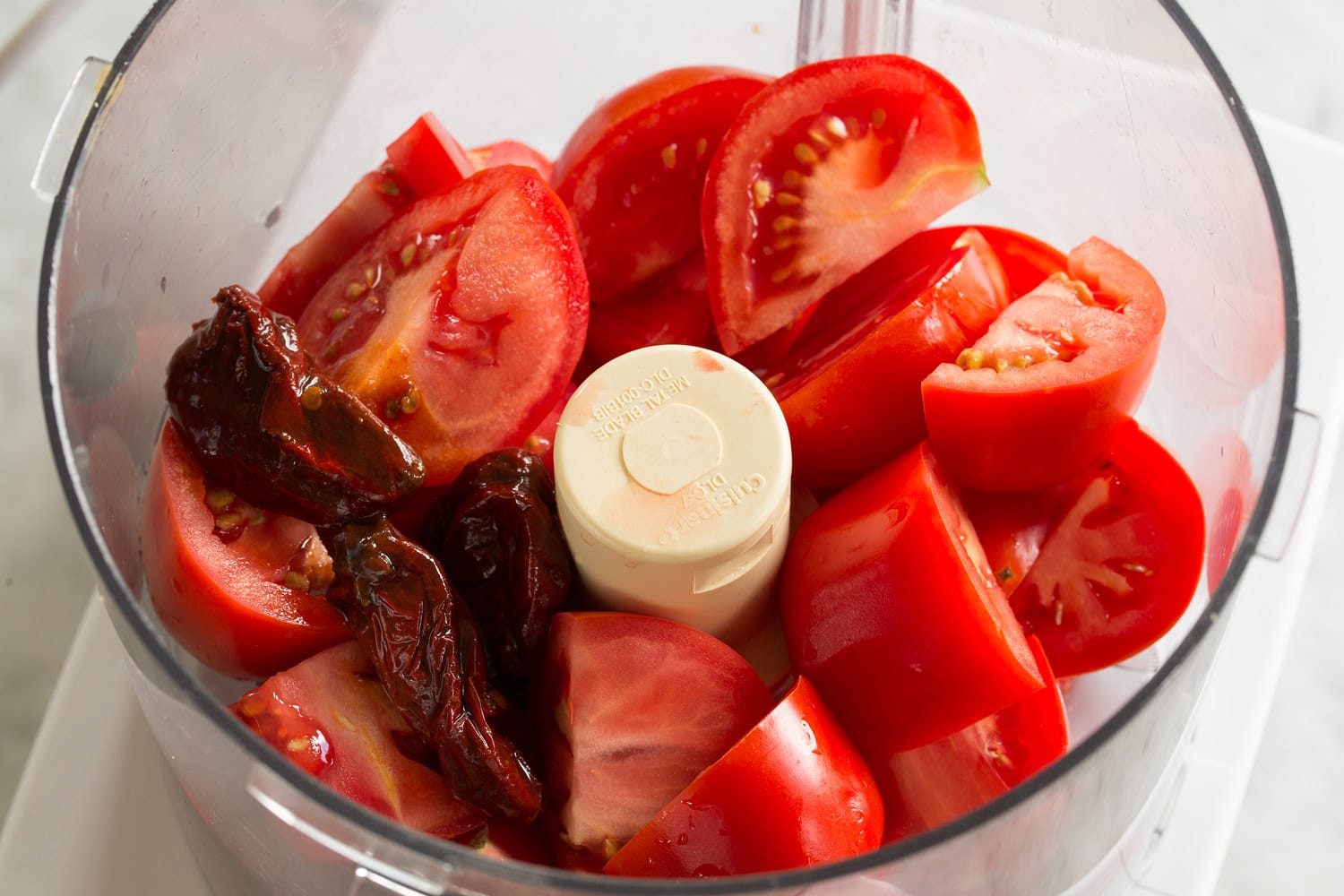 Quartered tomatoes in food processor before mincing.