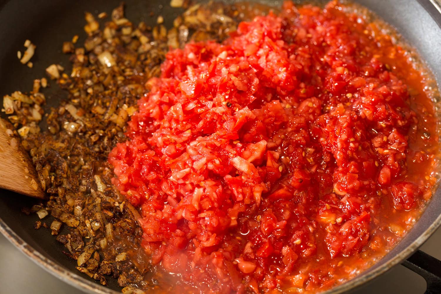 Minced tomatoes added to onion mixture in skillet.