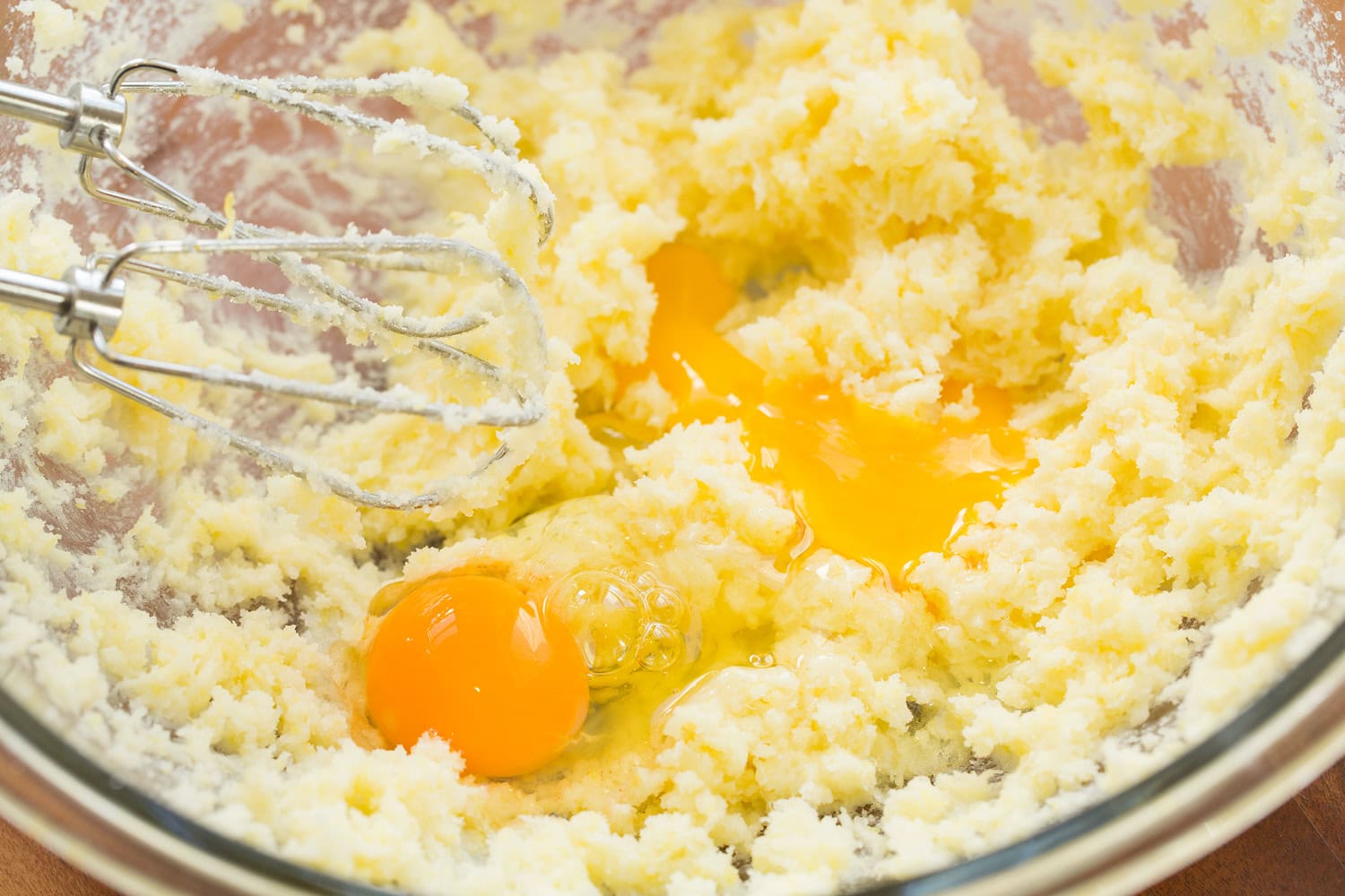 Creamed butter and sugar with eggs added in mixing bowl.