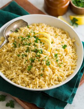 Bowl of lemon orzo set over a green cloth and a wooden tray.