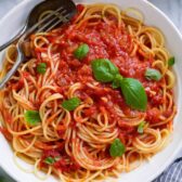 Marinara sauce tossed with spaghetti in a pasta bowl.