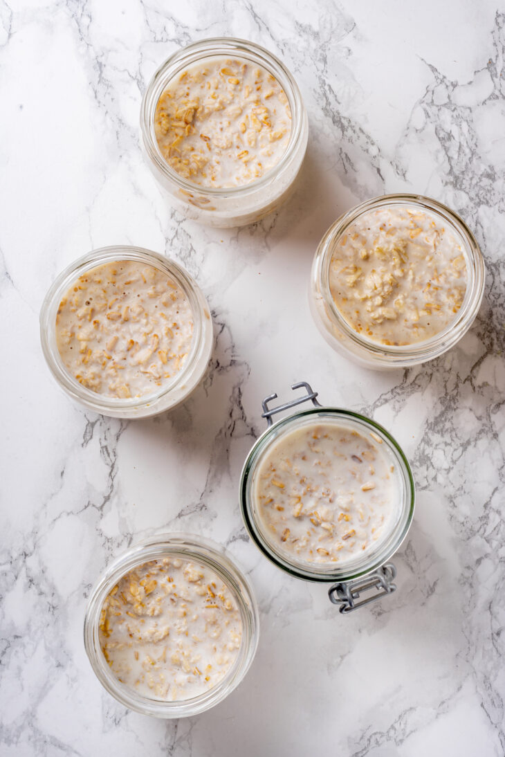 Overhead view of overnight oats portioned into five mason jars.