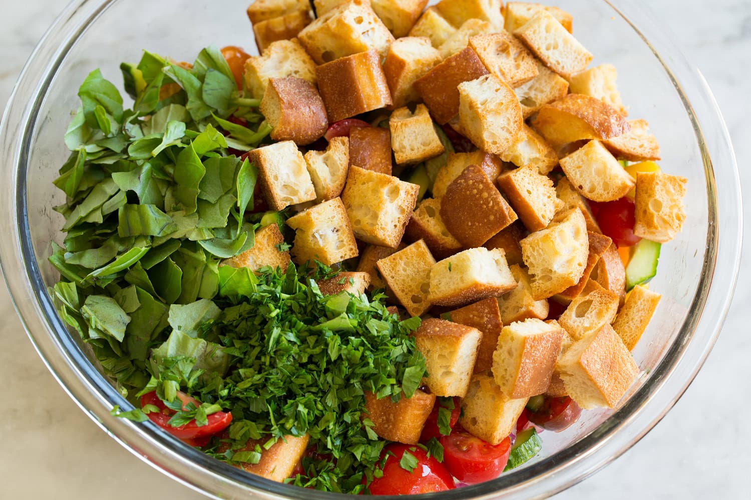 Toasted bread and herbs added to salad.