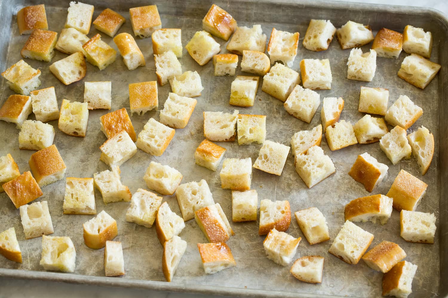 Bread cubes on a baking sheet before toasting in the oven.