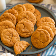 Pumpkin snickerdoodle cookies on a blue plate with white pumpkins and cinnamon sticks around it for decoration.