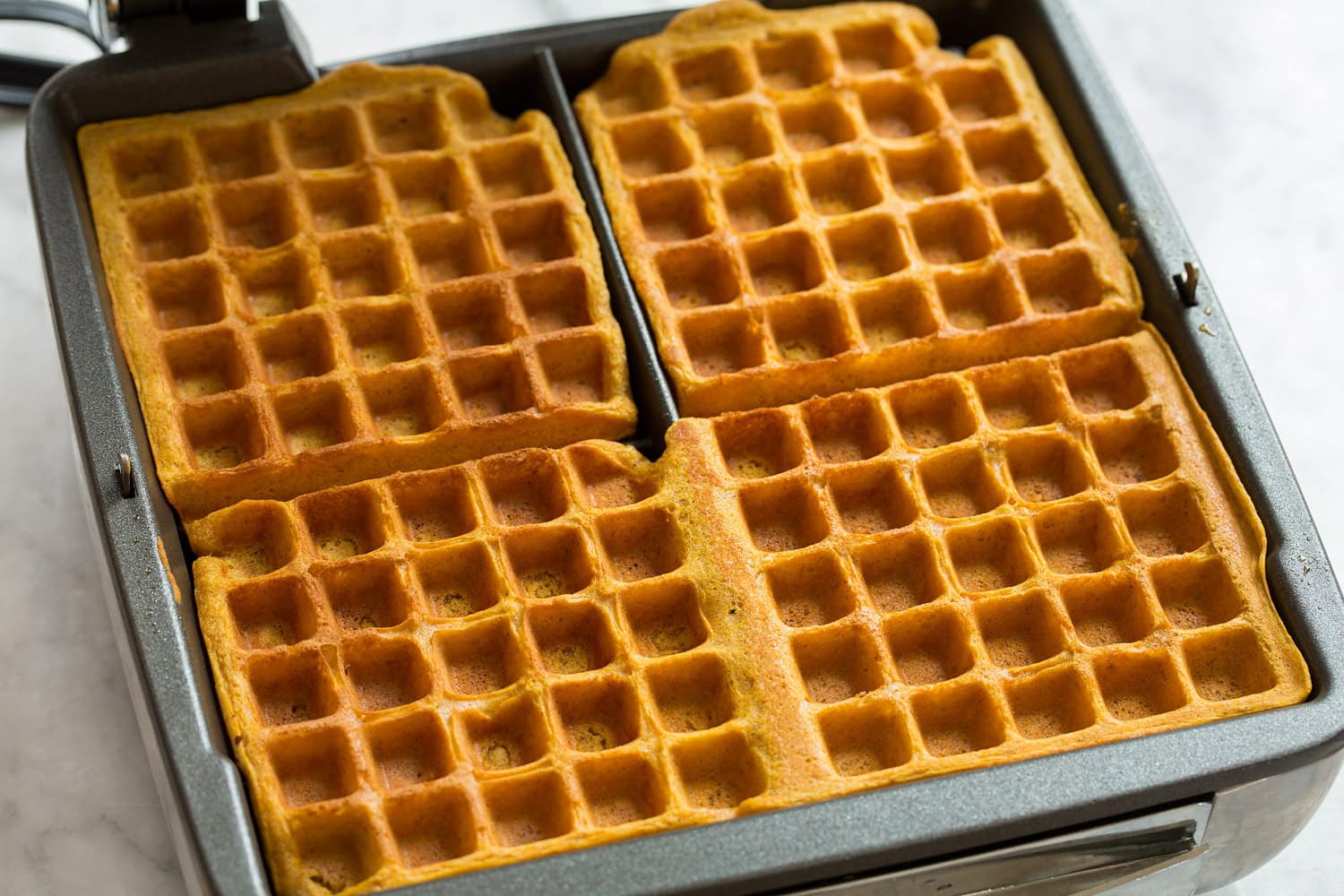 Completed pumpkin waffles in a waffle iron.