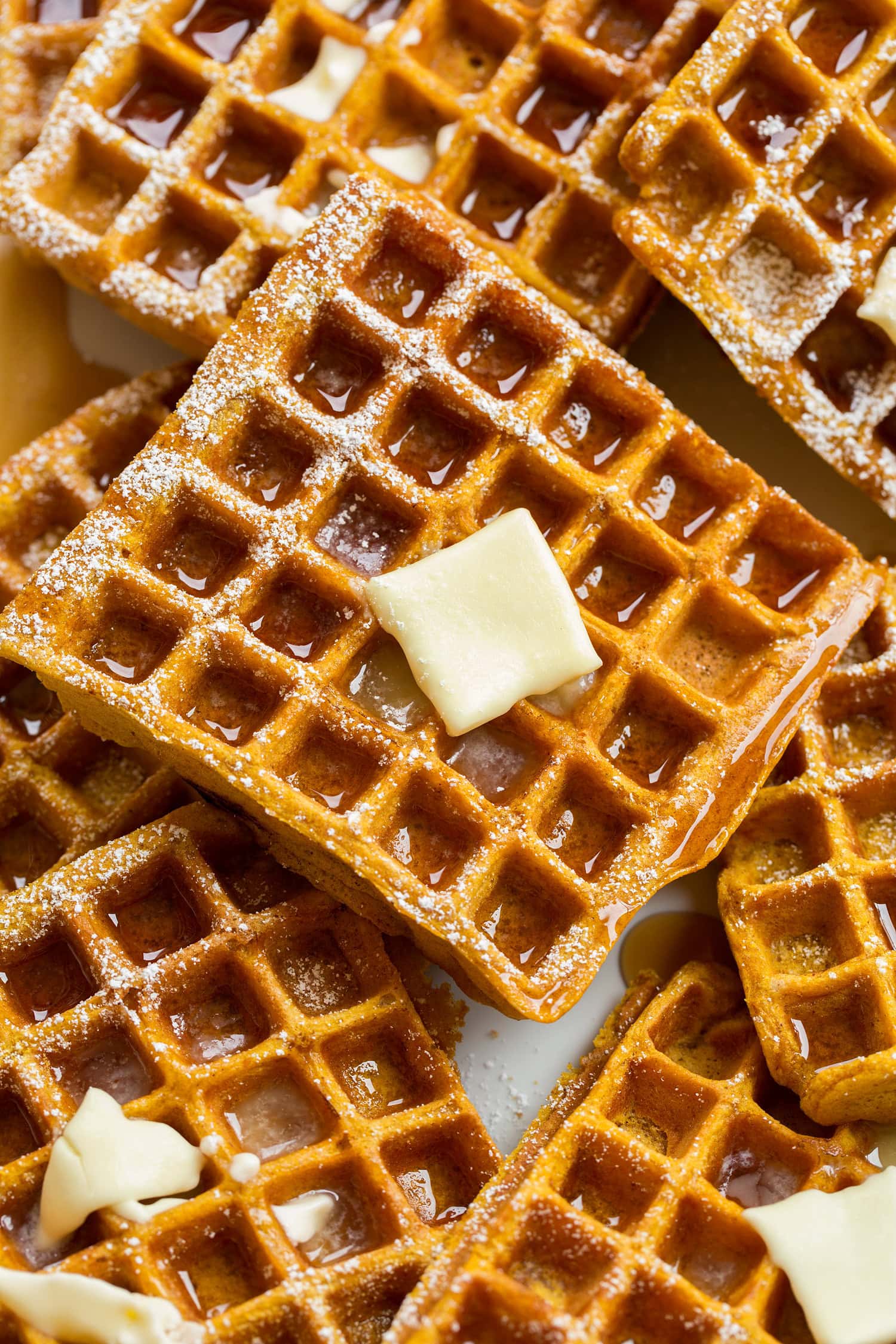 Close up photo of pumpkin waffle with syrup and butter.