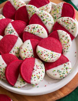 Red velvet shortbread cookies shaped in rounds, dipped in white chocolate and decorated with sprinkles.