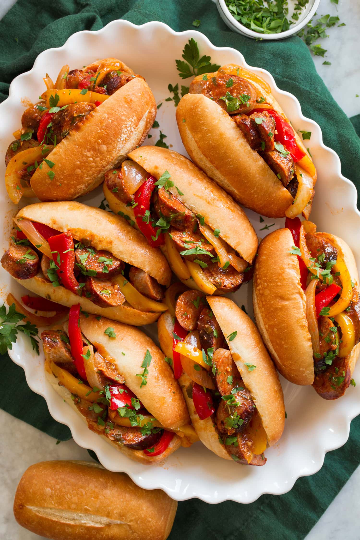 Sausage and peppers shown served in small hoagie buns.