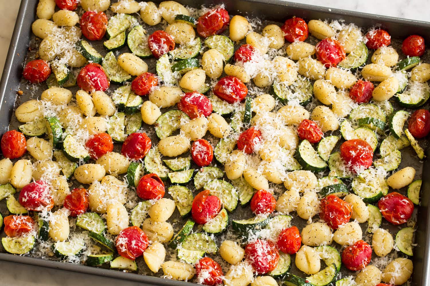 Baked sheet pan gnocchi with a parmesan sprinkled over.