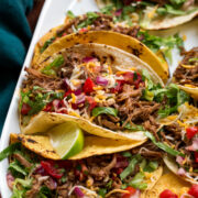 Close up photo of shredded beef tacos with toppings.