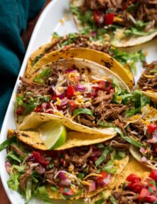 Close up photo of shredded beef tacos with toppings.