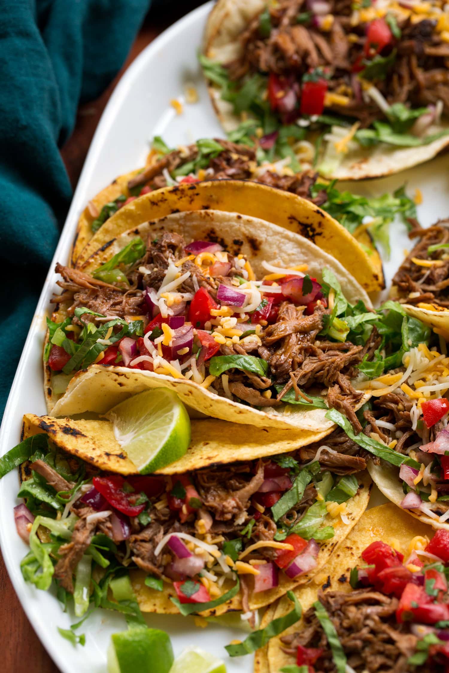 Close up photo of shredded beef tacos with toppings.