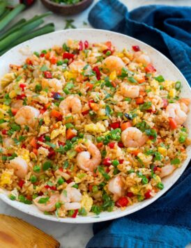 Large white serving bowl with shrimp fried rice set on a marble surface.