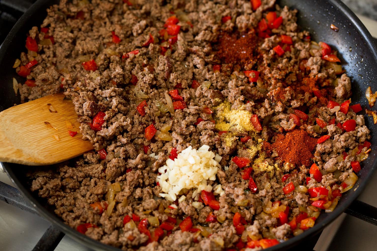 Garlic and spices added to crumbled browned beef.