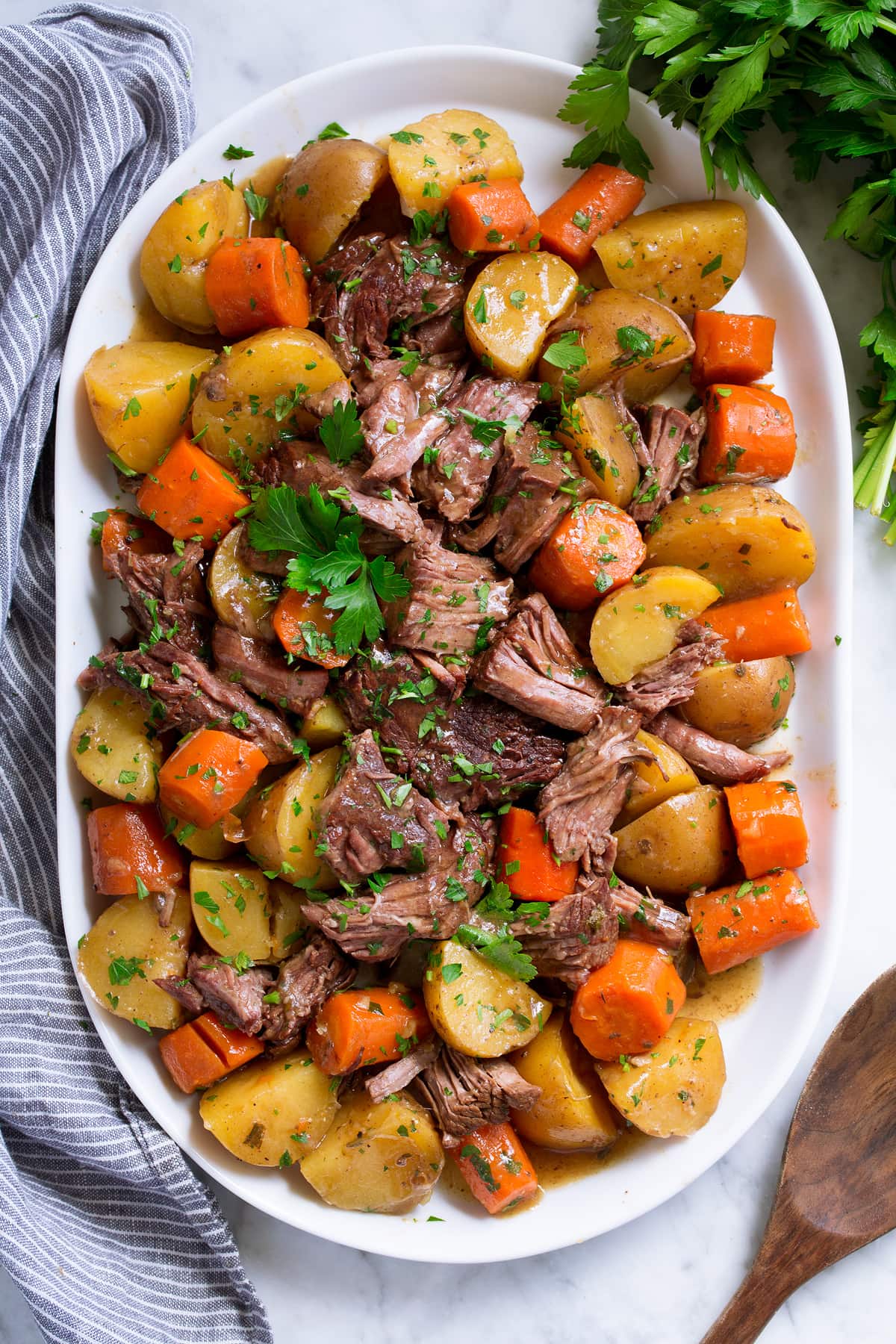 Slow Cooker Pot Roast with potatoes and carrots on a white oval serving platter set over marble.