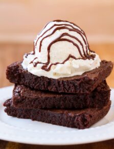 Stack of 3 brownies with ice cream and hot fudge sauce on top.