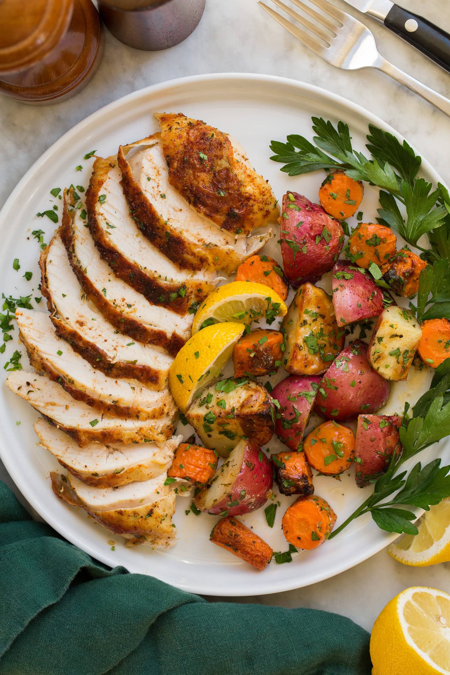 Sliced chicken with roasted vegetables to the side.