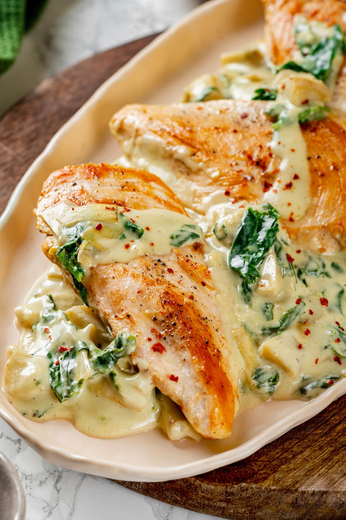 Creamy spinach artichoke chicken served on an oval platter.