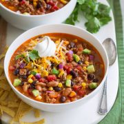 Two servings of taco soup in white bowls over a white platter.