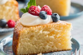 Slice of yogurt cake shown close up with yogurt and berries on top.